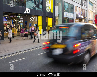 Ein unscharfer Taxi geht, die von einer Zweigniederlassung eines JD Sports Chain Store in London Stockfoto