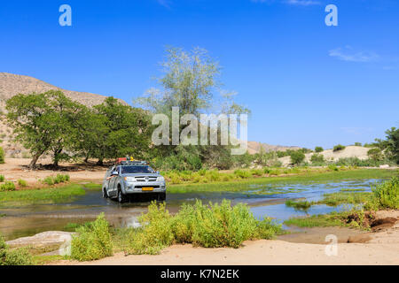 Off-road-Fahrzeug fährt durch Hoanib Fluß, Khowarib Schlucht, Damaraland, Kunene Region, Namibia Stockfoto