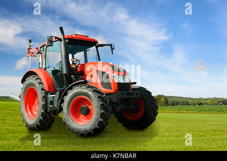 Das zusammengesetzte Bild eines modernen roten landwirtschaftlichen Generische Traktor auf einer grünen Wiese an einem sonnigen Tag. Mai darzustellen, Dritten IP. Stockfoto