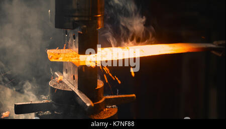 Schlosser schlägt das heiße Bügeleisen um die gewünschte Form zu geben. Stockfoto