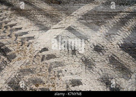 Muddy Reifenspuren auf Risse Fahrbahn vom Bauernhof Fahrzeuge - Frankreich. Stockfoto