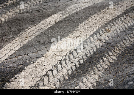 Muddy Reifenspuren auf Risse Fahrbahn vom Bauernhof Fahrzeuge - Frankreich. Stockfoto