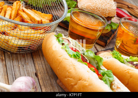 Hot Dogs, verschiedene Snacks und Bier auf einem Holztisch, close-up. Nationalen Tag hot dog usa Fast Food Stockfoto