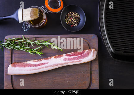 Bacon Strips mit frischen Gewürzen auf einem Holz ccutting Board. Stockfoto