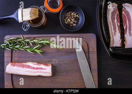 Bacon Strips mit frischen Gewürzen auf einem Holz ccutting Board. Stockfoto