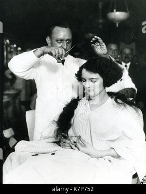 1920 - eine junge Frau, die ihr Haar "schief" in einem Männer Friseur. Stockfoto