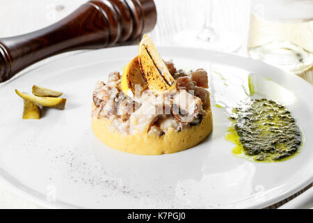 Stücke von Kaninchen geschmort in saurer Sahne Sauce mit Champignons mit Kartoffelpüree serviert. Auf weiße Platte. Stockfoto