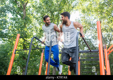 Zwei schöne junge Männer leidenschaftlich über Fitness dips Tun exerc Stockfoto