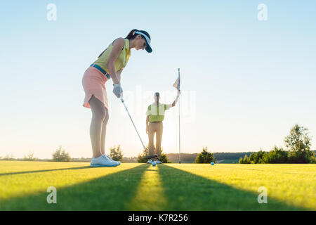 Passende Frau Ausübung schlagen Technik während der Golf Klasse mit einem Stockfoto