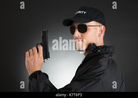 Porträt der jungen Leibwächter Holding Gun über schwarzen Hintergrund Stockfoto