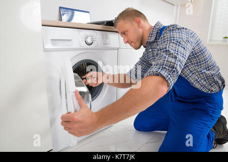 Junge männliche Techniker die Waschmaschine in der Küche Stockfoto