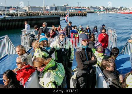 Menschen tragen warme Overalls reiten Boot während eine Whale Watching Tour aus Reykjavik. Stockfoto