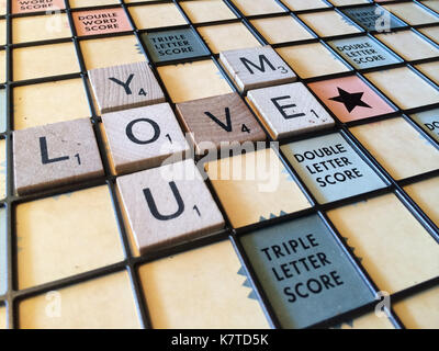 Die Worte "Sie lieben mich" heraus auf einem Scrabble-Spiel board geschrieben. Stockfoto