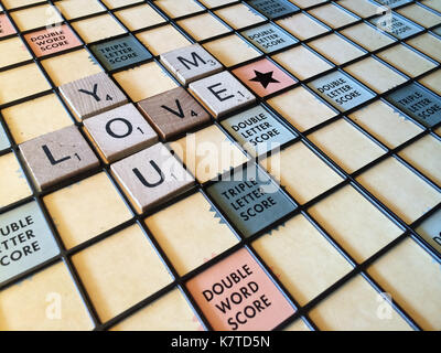 Die Worte "Sie lieben mich" heraus auf einem Scrabble-Spiel board geschrieben. Stockfoto