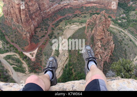 First Person Perspektive Schuß von einem Wanderer, die am Rand einer Klippe sitzen an Angel's Landing im Zion National Park. Stockfoto