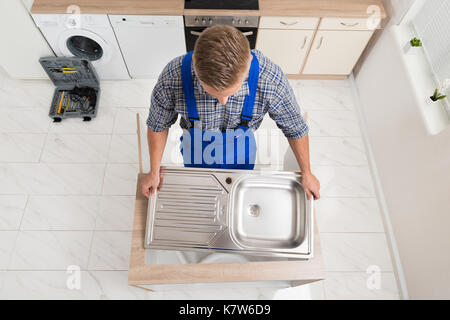 Hohe Betrachtungswinkel der männlichen Klempner zur Festsetzung Waschbecken aus Edelstahl Stockfoto