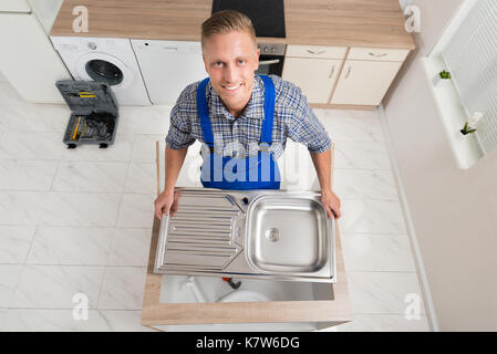 Hohe Betrachtungswinkel der männlichen Klempner zur Festsetzung Waschbecken aus Edelstahl Stockfoto