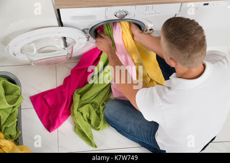 Hohe Betrachtungswinkel und der junge Mann mit Waschmaschine Gerät zu Hause Stockfoto