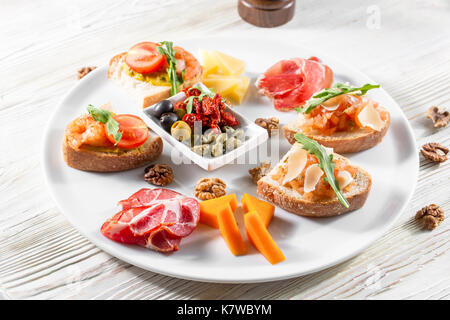 Auswahl an leckeren Bruschetta oder Häppchen auf taosted Baguette und Quark Käse garniert mit geräuchertem Lachs, Garnelen. Stockfoto