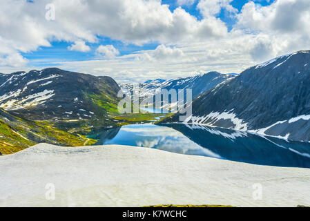 Mountain Lake Djupvatnet mit Reflexion und Schneefeld im Vordergrund, unter dem Berg Dalsnibba in der Nähe Geiranger, Norwegen Stockfoto