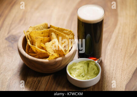 Dunkles Bier mit Nachos und guacamole Sauce Stockfoto