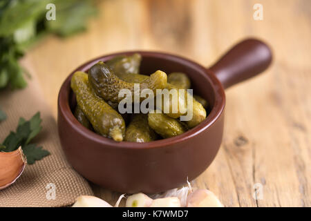 Eingelegte Gurken oder Gurken in der Schüssel auf Holz rustikale Tabelle von oben. Makro. Stockfoto