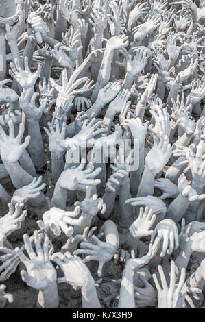 Greifende Handskulpturen symbolisieren ungebremste Begierde an der Brücke des 'Zyklus der Wiedergeburt' im Wat Rong Khun (Weißer Tempel). Chiang Rai, Thailand Stockfoto