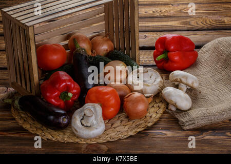 Frisches Gemüse in umgeworfen Holzbox mit sackleinen über Holz- Hintergrund Stockfoto