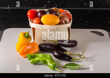 Frisch geerntete Tomaten, Sweet orange und grüne Paprika und Auberginen. Auf Zähler nach oben an Bord genommen. Stockfoto