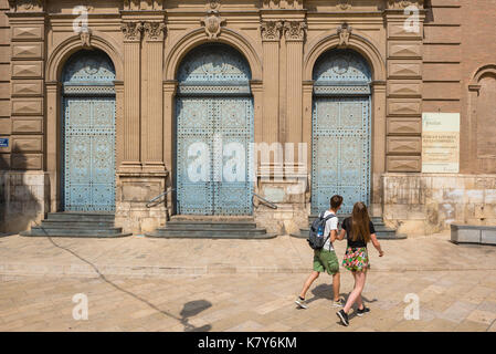 Reisen junge Leute, Rückansicht von zwei jungen Reisenden, die die Türen einer barocken Kirche betrachten, während sie durch die Altstadt von Valencia gehen. Stockfoto
