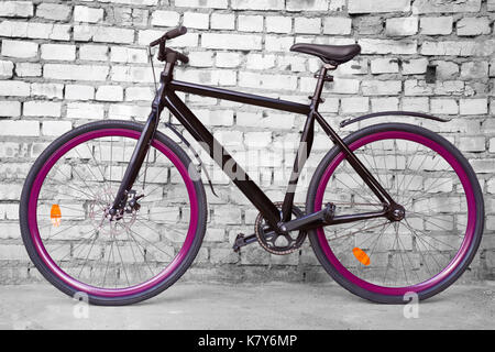 Schwarz feste Urban Bike mit violetten whels gegen schwarze und weiße Wand Stockfoto