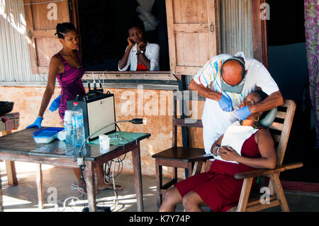 Freiwillige italienische Zahnarzt bei der Arbeit mit lokalen madagassischen Patienten auf seinem Hotel bungalow Veranda, ambatoloaka Strand, Nosy Be Madagaskar Stockfoto