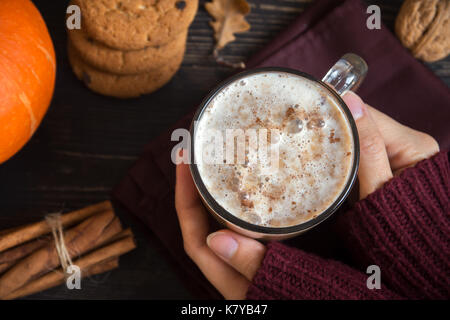 Pumpkin Spice Latte in weibliche Hände. Frau trinken Latte mit saisonalen Herbst Gewürze und Cookies. Traditionelle Kaffee Trinken für die Herbstferien. Stockfoto