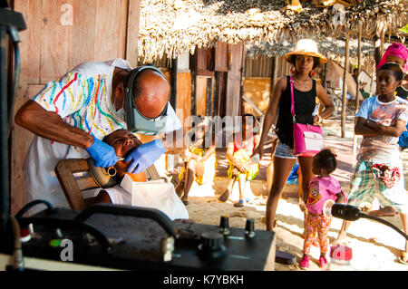 Freiwillige italienische Zahnarzt bei der Arbeit mit lokalen madagassischen Patienten auf seinem Hotel bungalow Veranda, ambatoloaka Strand, Nosy Be Madagaskar Stockfoto