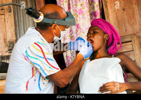 Freiwillige italienische Zahnarzt bei der Arbeit mit lokalen madagassischen Patienten auf seinem Hotel bungalow Veranda, ambatoloaka Strand, Nosy Be Madagaskar Stockfoto