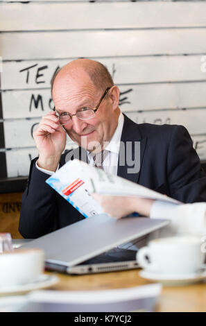 Senior Manager, CEO, in Gespräch schaut weg hält die Brille in der Hand. Vertikale Portrait, candid Shot Stockfoto