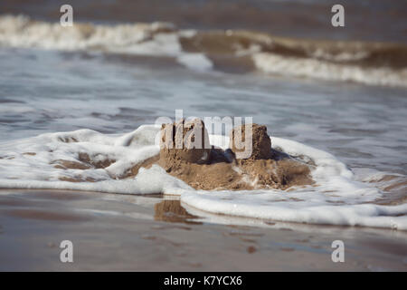 Wellen der Irischen See, der das Wegspülen Sandburgen bei Formby, England Stockfoto