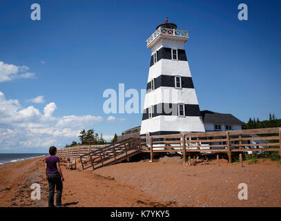 Frau geht in Richtung West Point Lighthouse auf North PEI's Shore, Kanada Stockfoto