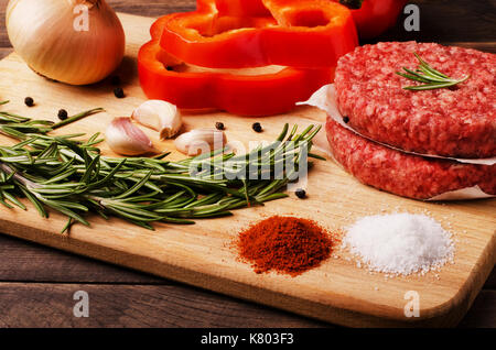 Rohes Hackfleisch burger Schnitzel mit roten Zwiebeln, Knoblauch, Olivenöl und roter Pfeffer Öl zum Braten im Backofen zubereiten, close-up Stockfoto