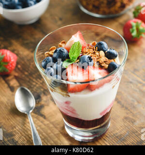 Joghurt mit Müsli, Blaubeeren und strawberies in Glas auf Holztisch. gesunder Snack, gesundes Frühstück Stockfoto