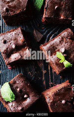 Dark chocolate Brownies mit minzeblatt auf dunklem Hintergrund eingerichtet. top Aussicht, vertikalen Zusammensetzung Stockfoto