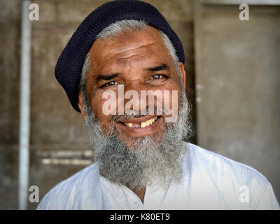 Älterer indischer Moslem-Mann mit islamischem Bart, Zahnlücke und muslimischem Gebetstich (Zebibah) auf der Stirn lächelt für die Kamera. Stockfoto