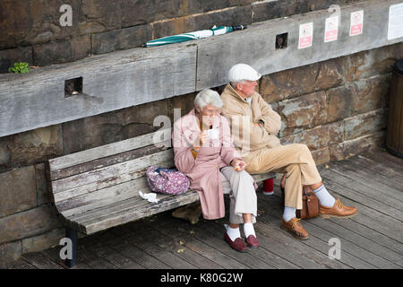 Ein älteres Paar sitzen auf einer Bank, die Freizeit genießen. Stockfoto