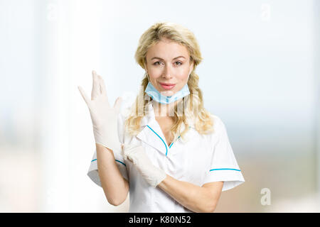 Junge Krankenschwester auf Handschuhe. Stockfoto