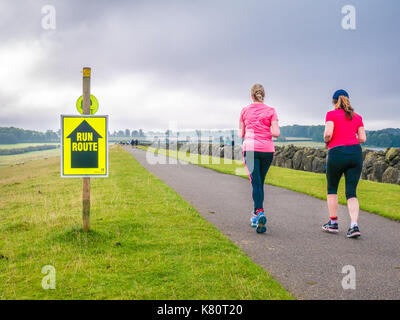 Bringen Sie den hinteren, der letzte Läufer auf dem Weg über den Damm zu Beginn der Rutland Marathon und Halbmarathon Rennen in Rutland Water Reservoir, England, am Sonntag, den 17. September 2017 Stockfoto