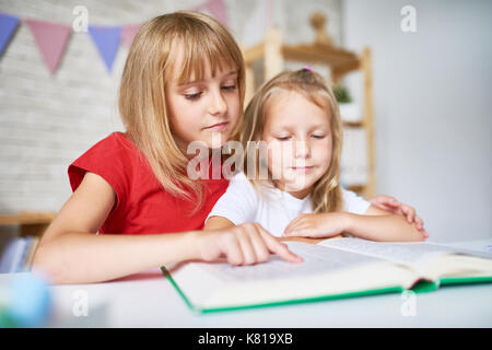 Kleinen Schwestern auf das Lesen konzentrieren Stockfoto