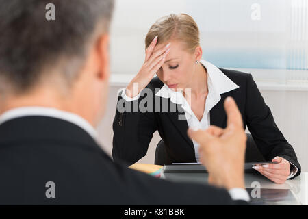 Nahaufnahme der Unternehmer Streiten für junge geschäftsfrau am Schreibtisch Stockfoto