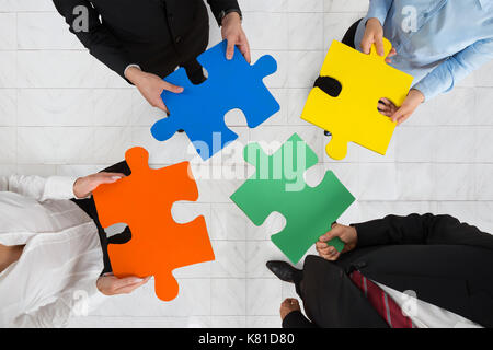 Hohe Betrachtungswinkel aus Geschäftsleuten Team Holding bunte Puzzleteile in den Händen Stockfoto