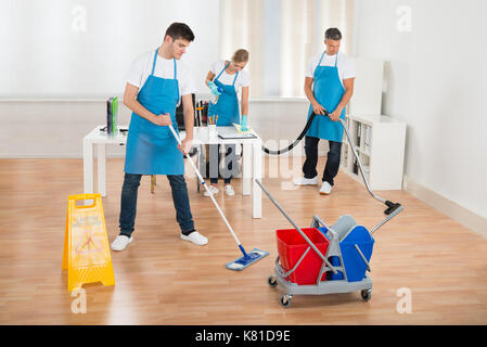 Reiniger Team in Uniform Reinigung Holzboden im Büro Stockfoto