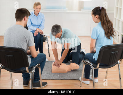 Männliche Kursleiter Unterricht Erste Hilfe CPR-Technik zu Seinen Studenten Stockfoto